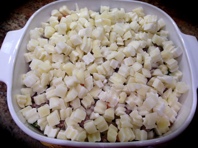 Arrange an even layer of frozen potatoes over the meat...